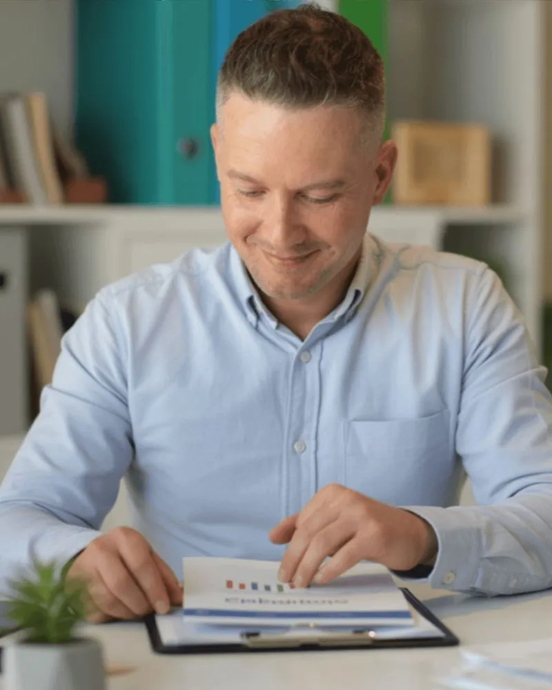Joshua reviewing bookkeeping paperwork at a desk for a contractor business.